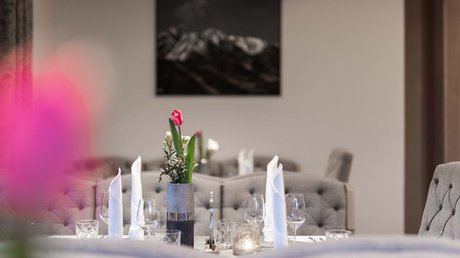 Einblicke in unser Hotel im Stubaital in Fulpmes Eleganter gedeckter Tisch mit roten Tulpen und weißen Servietten in modernem Restaurant