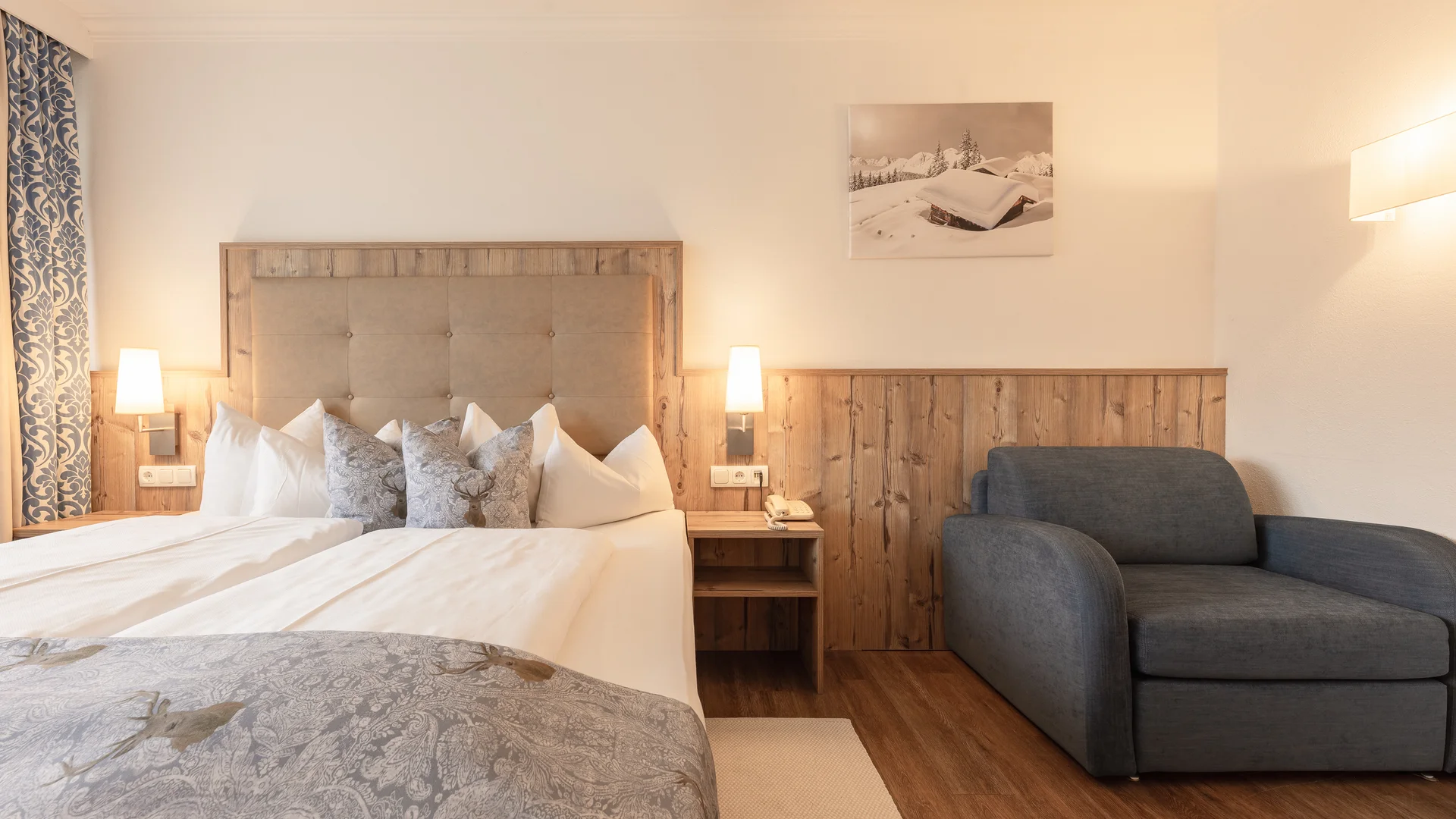 Hotel room with double bed, armchair, wood paneling and winter landscape picture