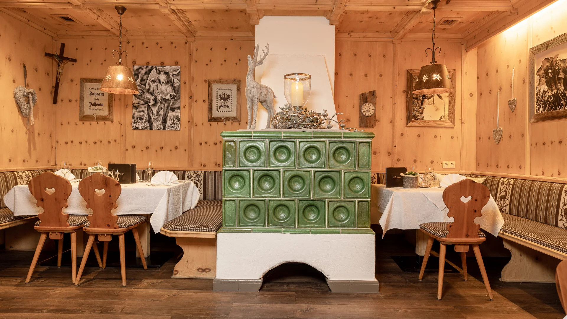 Rustic dining room with green tiled stove, wood paneling and set tables
