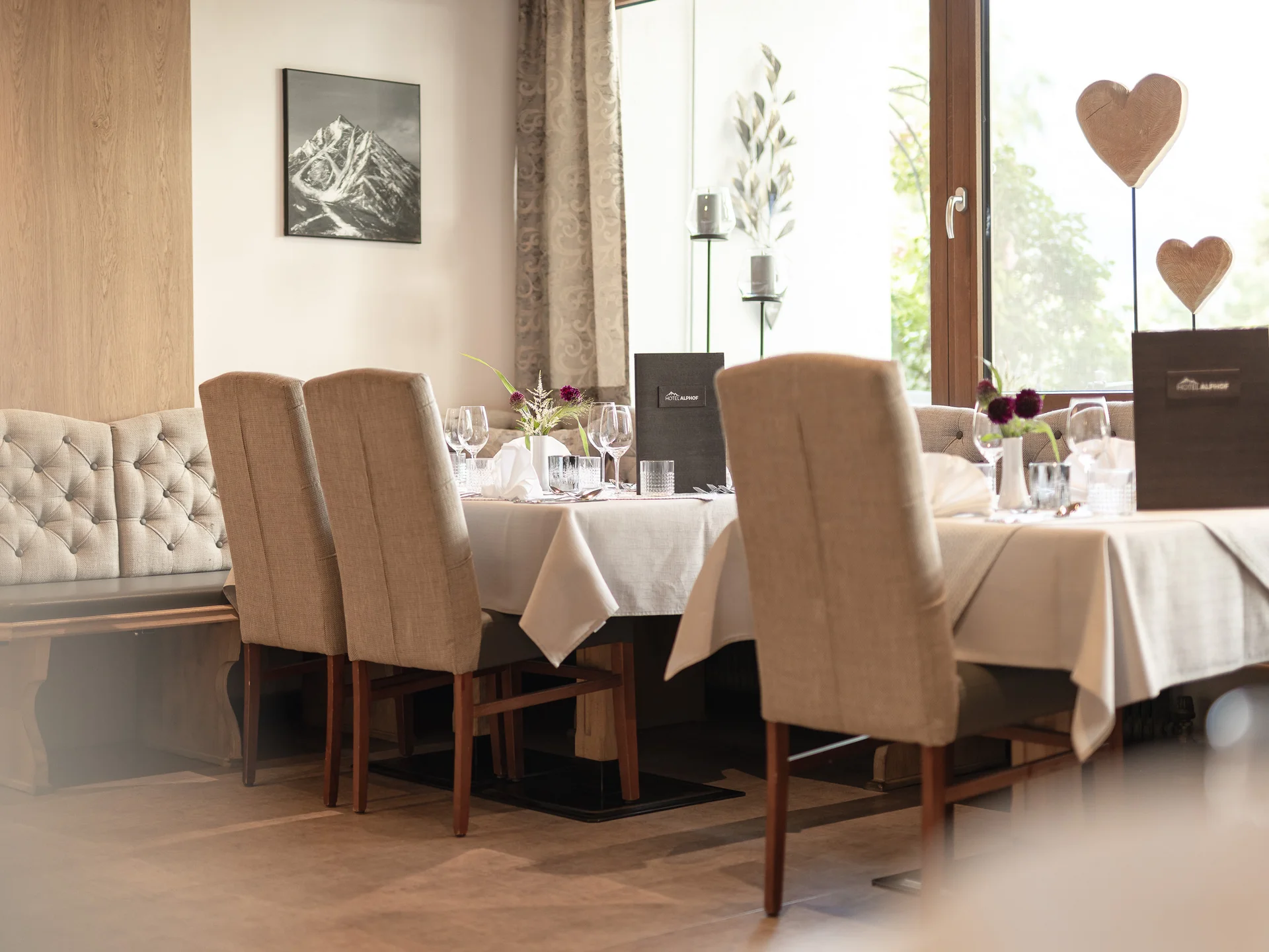 Alphof | genuine indulgence at a gourmet hotel in Tyrol Elegant restaurant with set tables, upholstered bench and large windows