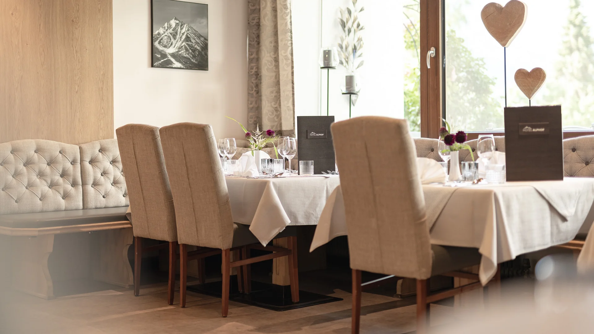 Elegantes Restaurant mit gedeckten Tischen, Polsterbank und großen Fenstern