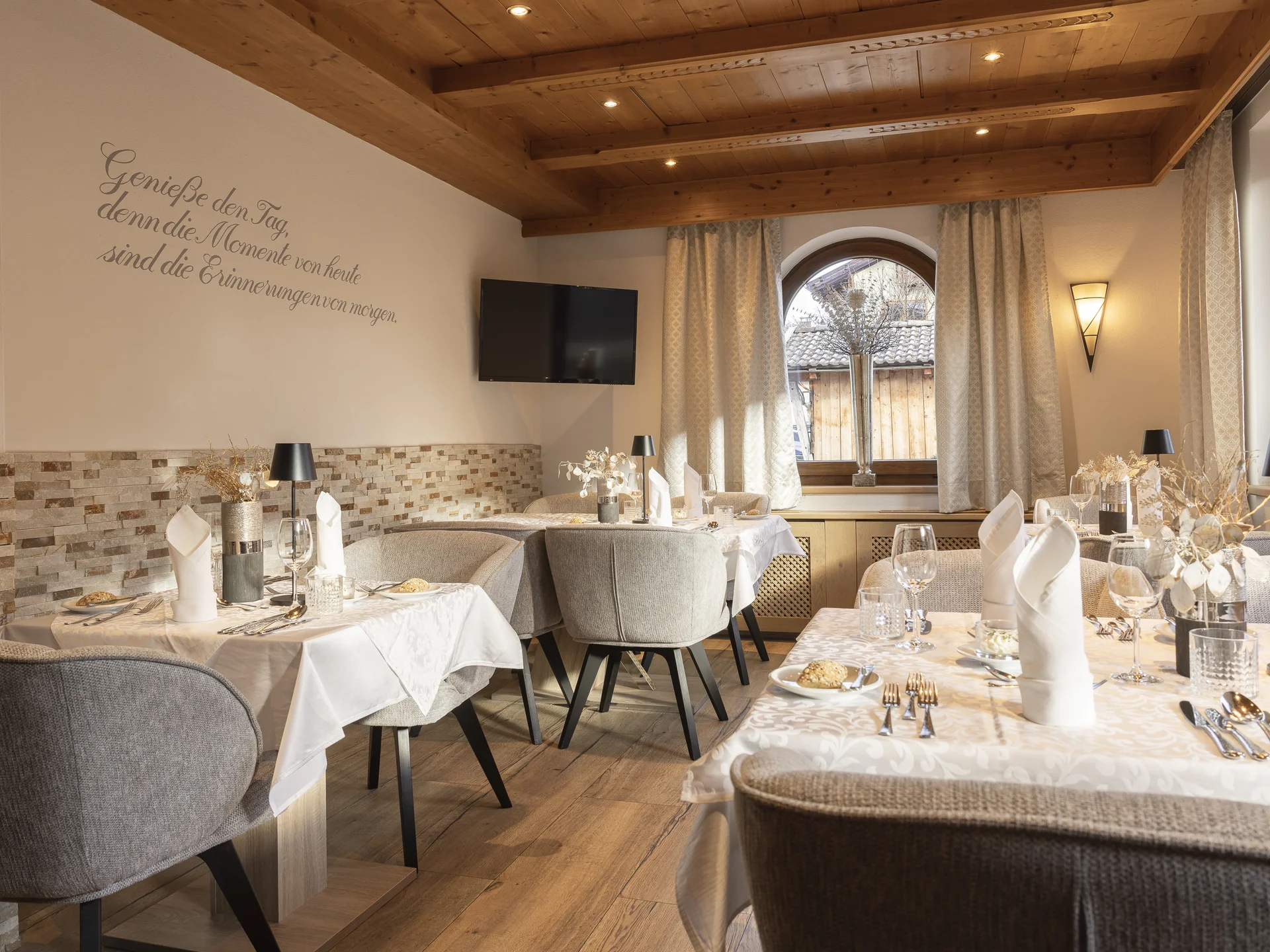 Alphof | genuine indulgence at a gourmet hotel in Tyrol Elegant restaurant with set tables, a wooden ceiling and large windows