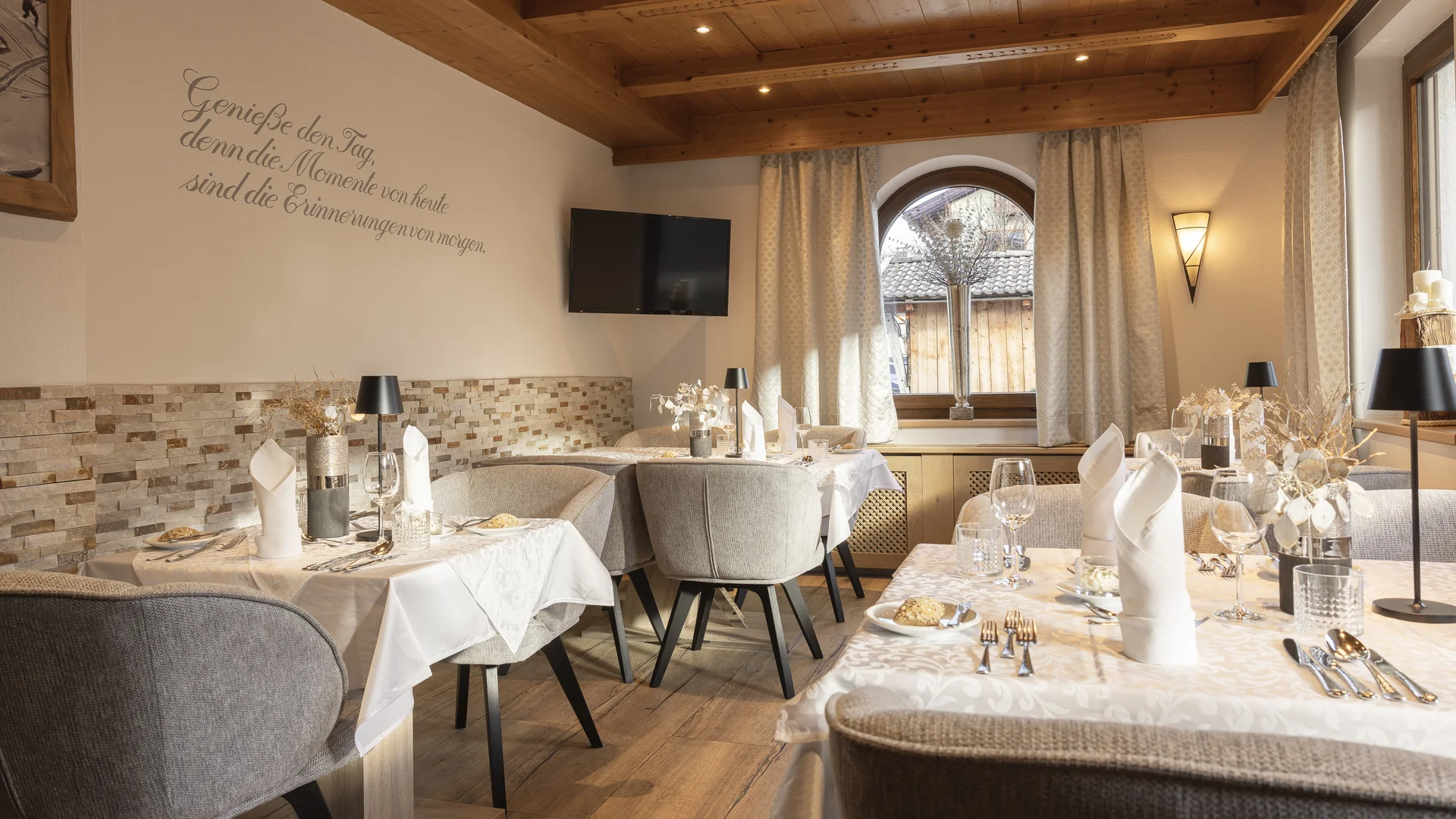 Elegant restaurant with set tables, a wooden ceiling and large windows